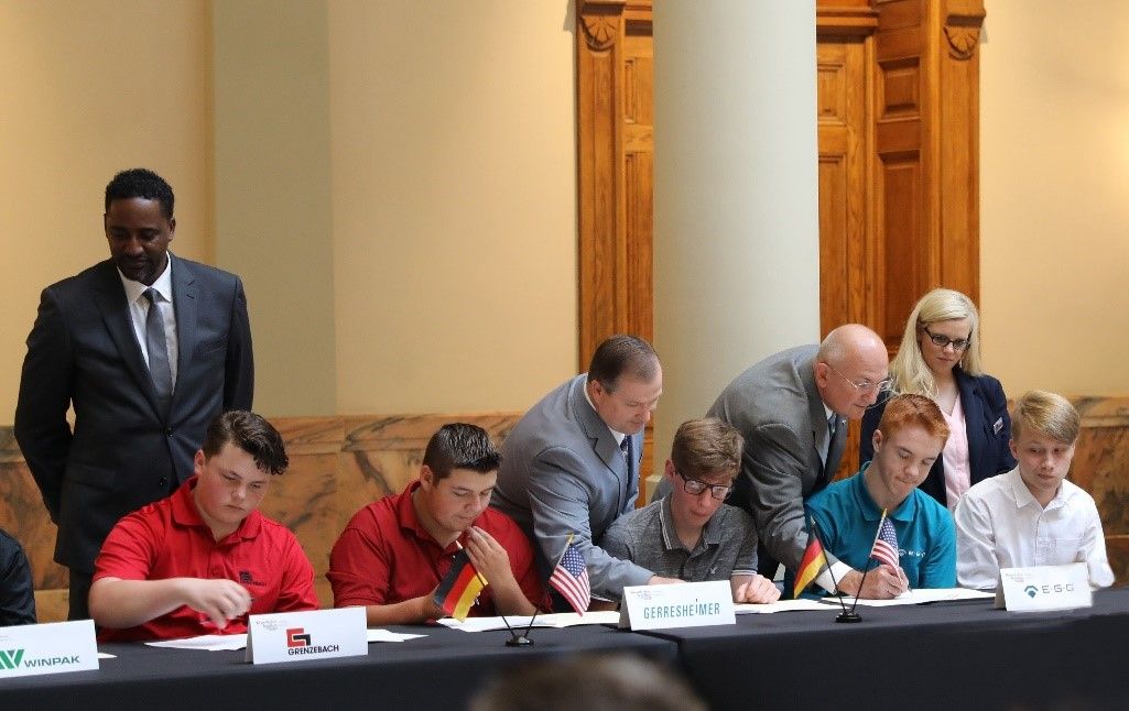 Die ersten Auszubildenden des Bundesstaates Georgia unterzeichnen ihre Verträge in einem feierlichen Rahmen gemeinsam mit den Vertretern der Außenhandelskammer.