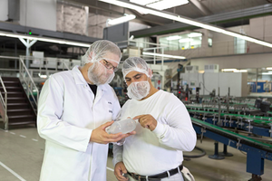 Marian Ferlic-Eisermann (l.) prüft mit einem Kollegen einen Glasbehälter. 